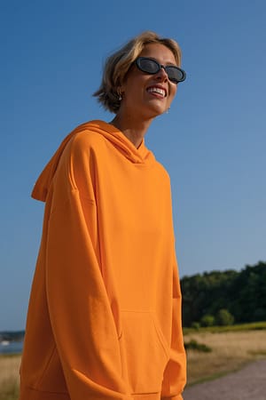 Orange Oversize-Kapuzenpullover mit Tasche aus ökologischem Material